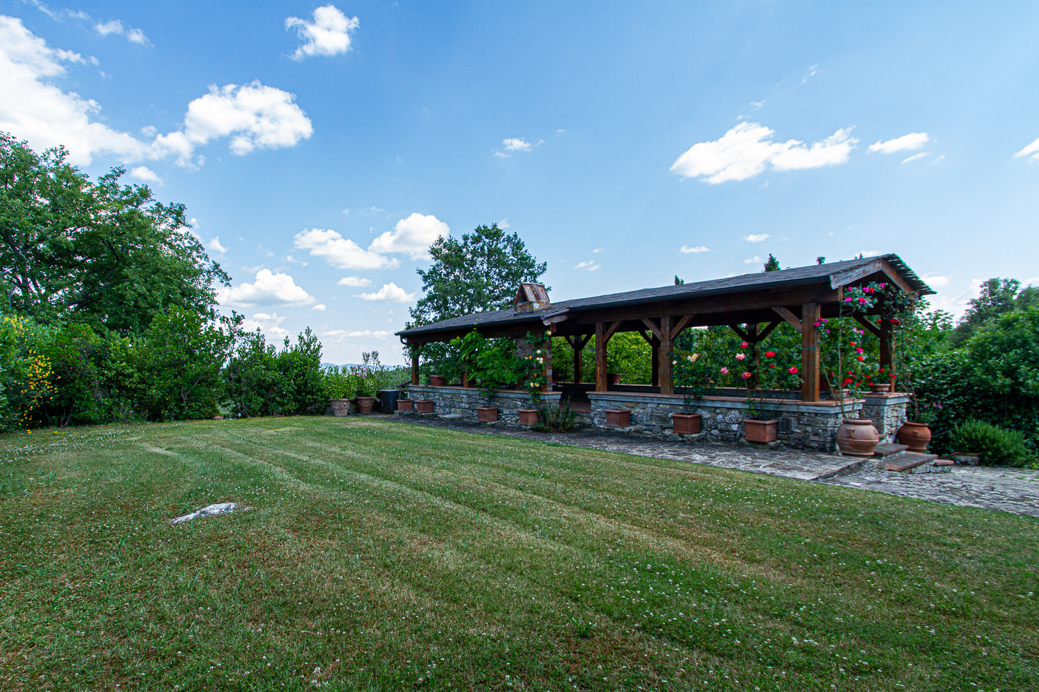 Gazebo in legno con muretto in pietra e giardino