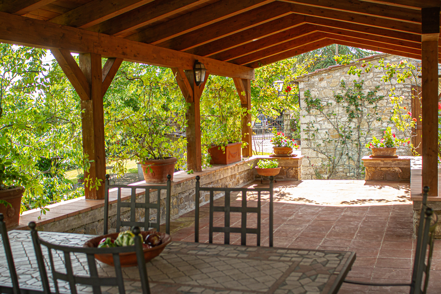 Veranda con zona pranzo, rose e muro in pietra